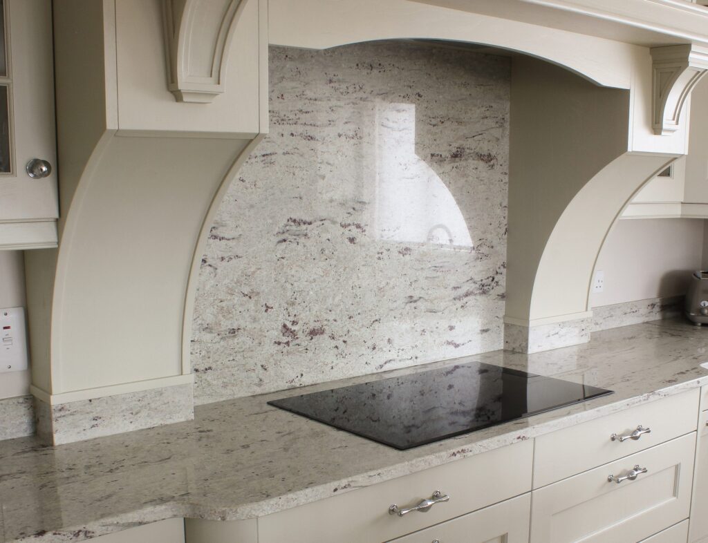 Polished white granite splashback with pink veining in cream arched traditional kitchen