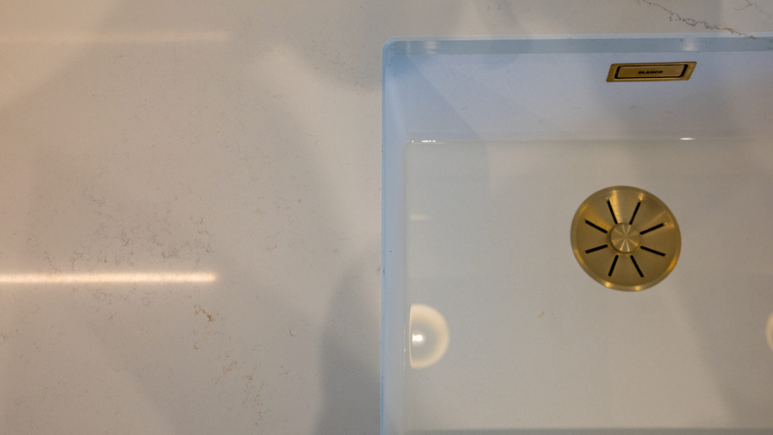 Blanco undermount sink white quartz worktop with brushed gold brass waste drain detail