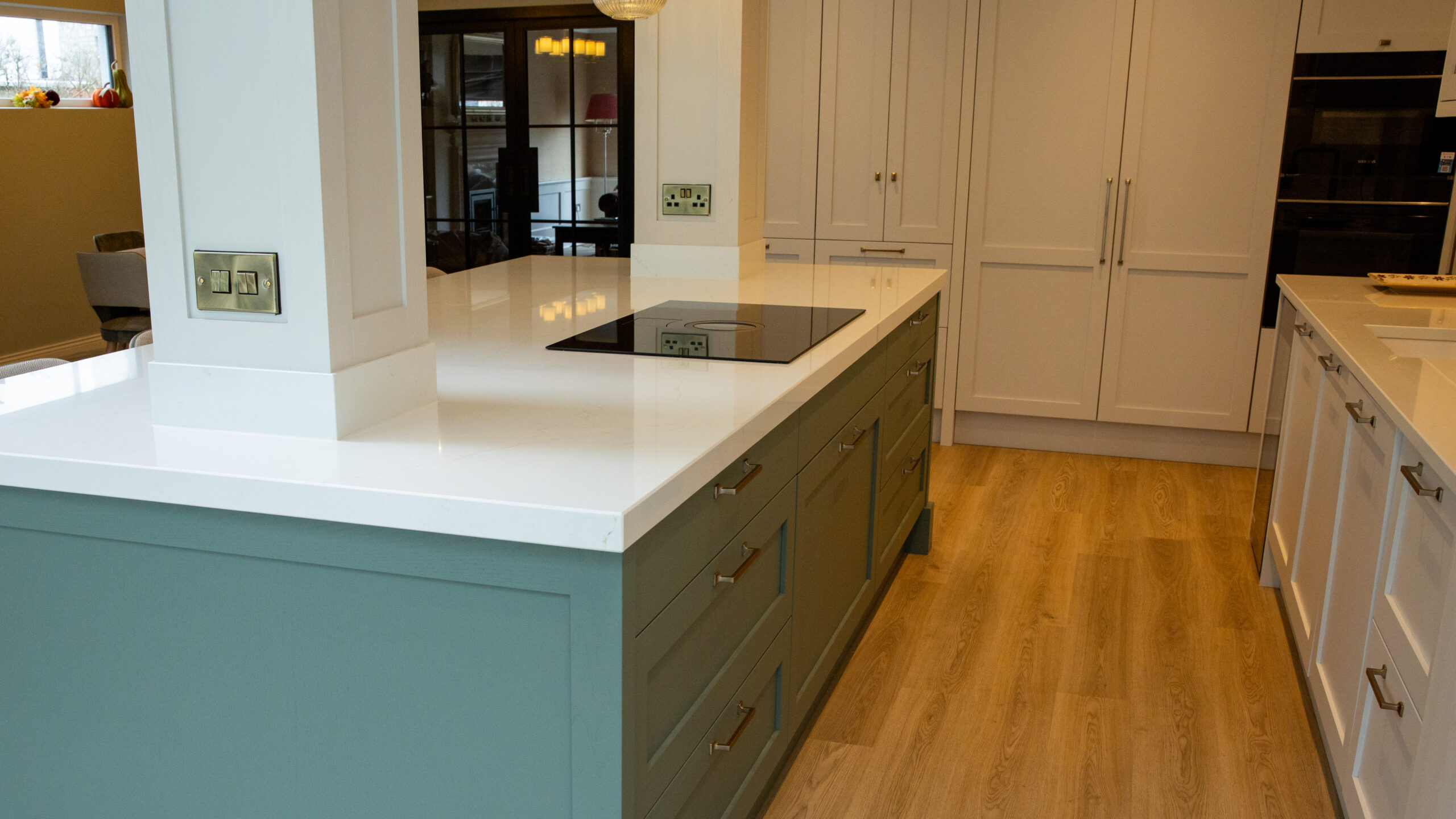 Sage green kitchen island with white quartz worktop, induction hob and shaker style cabinets